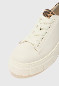 Sneaker in pelle bianca con una suola spessa e segmentata e dettagli beige texturizzati. Presenta un rivestimento con stampa leopardata e lacci piatti.