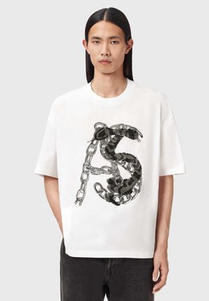 Biała bawełniana koszulka z krótkimi rękawami, z czarnym nadrukiem łańcucha i węża na przodzie. Luźny krój z okrągłym dekoltem.