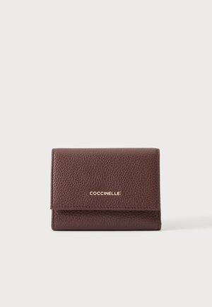 Portefeuille en cuir marron texturé avec logo doré « Coccinelle » centré sur le rabat avant, sur un fond clair uni.