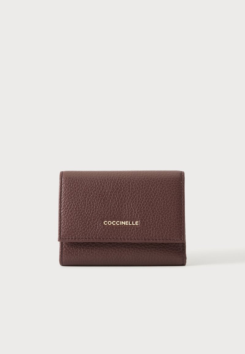Portefeuille en cuir marron texturé avec logo doré « Coccinelle » centré sur le rabat avant, sur un fond clair uni.