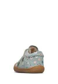 Dziecięcy miękki but z zieloną kwiecistą tkaniną, brązową fakturowaną podeszwą i puszystą wyściółką, widoczny z tyłu.