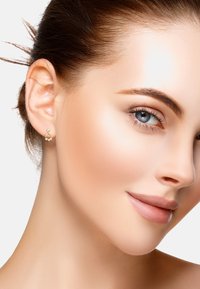 Guldörhängen med en delikat design och tre små sfärer. Närbild som framhäver den släta ytan och den glänsande finishen.