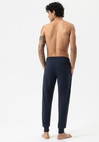 Marineblauwe joggers met een elastische tailleband, gekruiste enkels en een achterzak. Gemaakt van een zachte, lichte stof.