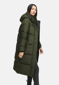 Grøn polstret lang frakke med hætte, der har lynlås fortil, trykknapper og ribbede manchetter. Glat tekstur og struktureret design.