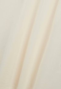 Tessuto di crema chiara con texture liscia, che presenta una leggera lucentezza, un lieve drappeggio e pieghe minime. Nessun motivo o elemento di metallo visibile.