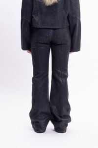 Mustat farkut, joissa on leveä alaosa ja kankaan tekstuuri, varustettuna takataskuilla ja näkyvillä ompeluilla. Yhdistetty yhteensopivaan lyhytvaippaiseen takkiin.