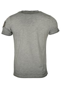 Grå t-shirt med kort ärm som har rund hals, strukturerad tyg och ett patch med ränder på vänster axel. Enkel design.