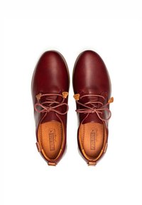 Zapatos de cuero burdeos con punta redonda, cordones de cuero y acentos en color beige. Las plantillas están acolchadas y llevan un logotipo en el lado interior.