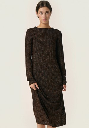 Long black dress with ribbed texture, featuring orange flecks. Crew neckline and long sleeves, reaching mid-calf with a loose fit.