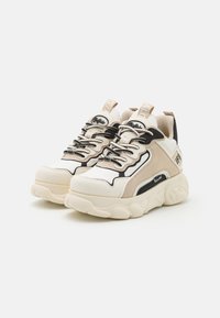 Tjocka sneakers i en blandning av vita, beige och svarta material. Texturerade ytor, framträdande snörning och logotypdetaljer på hälen.