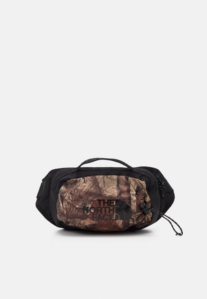 Zwart en bruin camouflage heuptasje met een handvat aan de voorkant, verstelbare riem en "The North Face" logo op het voorvak.