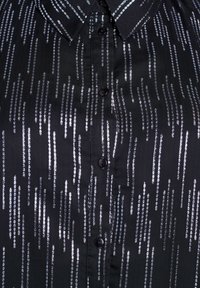Camicia nera con colletto, caratterizzata da motivi verticali di paillettes argentate e bottoni neri lungo il davanti. Tessuto dalla texture liscia.