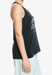 Czarny top na ramiączkach o luźnym kroju, z dekoltem w serek i białym napisem graficznym. Wykonany z miękkiego materiału, z szerokimi wycięciami na ramiona i bocznymi szwami.