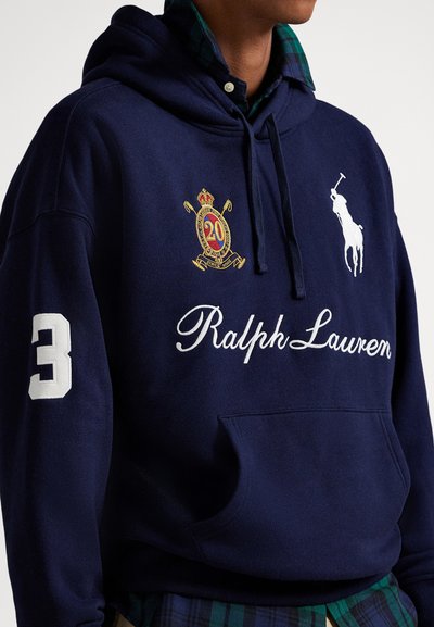 Μπλε σκούφο φούτερ με λευκό κείμενο "Ralph Lauren", κεντημένο λογότυπο παίκτη πόλο, έμβλημα "20" στο στήθος, και λευκό αριθμό "3" στο αριστερό μανίκι.