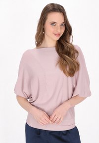 Maglione oversize rosa chiaro con maniche corte e larghe e orlo a costine. Texture morbida e leggero lucido, con motivi a coste diagonali.