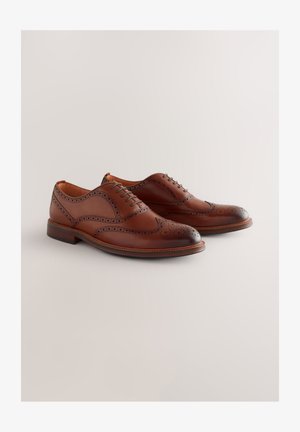 Zapatos oxford de cuero marrón con diseño de ala de mosca, detalles perforados y puntera lisa. Cuenta con un tacón bajo resistente y cierre de cordones.