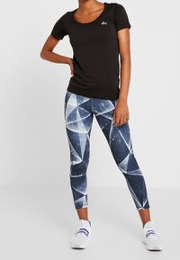 Svart topp med kortärm i kombination med leggings med geometriskt mönster i blått och vitt, med en slät struktur och åtsittande design.