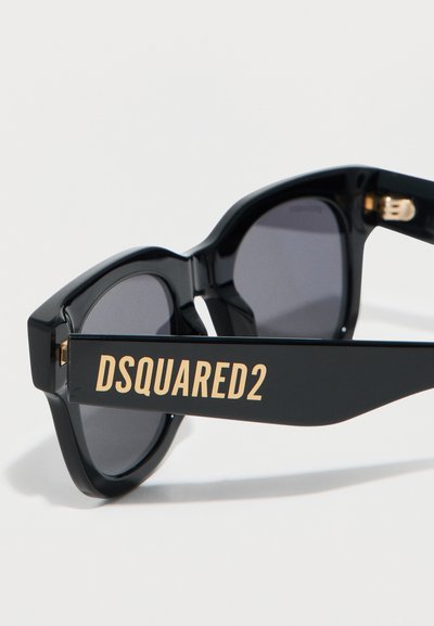 Μαύρα ορθογώνια γυαλιά ηλίου με σκούρους φακούς και χρυσό λογότυπο "DSQUARED2" στα χοντρά στεφάνια, παρουσιάζονται με φόντο το λευκό.