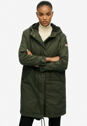 Parka à capuche vert olive avec un col en sherpa, taille ajustable à cordon, poignets boutonnés et deux poches avant.