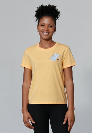 T-shirt en coton jaune à manches courtes avec une illustration d'un cahier bleu et un crayon sur la poitrine, col rond et coupe décontractée.
