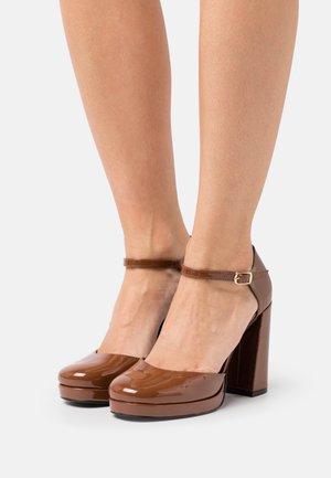 Brown patent leather high-heeled shoes with a rounded toe, adjustable ankle strap, and chunky platform sole.