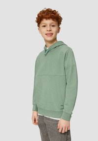 Muntgroene hoodie met een voorzak en een capuchon met trekkoord. In combinatie met grijze broek, bevat het geprinte tekst nabij de zoom.
