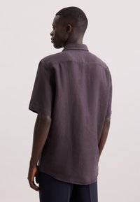 Korte mouwen, donkerpaarse shirt gemaakt van textuurstof met een kraag en een licht gebogen zoom aan de achterkant.