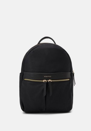 Sac à dos en nylon noir avec une forme arrondie, doté d'une poche zippée à l'avant, d'accents en matériel doré et d'une poignée sur le dessus.