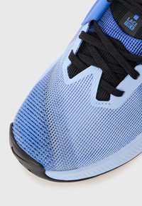 Blue athletic shoe featuring a textured upper with horizontal stripes, black laces, and a rubber sole with a prominent toe cap.