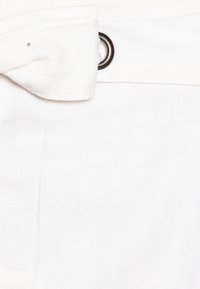 Tissu blanc au toucher lisse, présentant une boucle de ceinture avec un œillet en métal et une couture. Design minimaliste sans motifs.