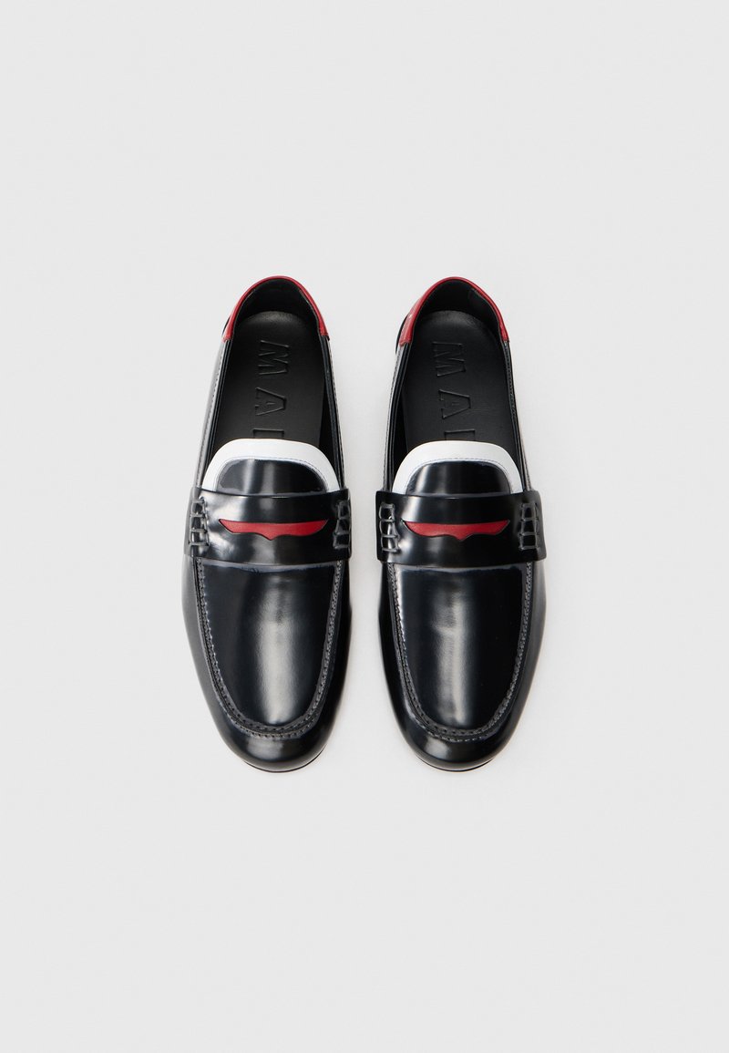 Sorte læder loafers med røde detaljer ved hælen og et hvidt bånd på overdelen. Glat tekstur og rund tå med syning detalje.
