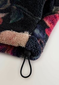 Koc polarowy z kwiatowym wzorem w ciemnych kolorach, o miękkiej fakturze i różowej spodniej stronie. Zawiera czarny sznurek do ściągania.