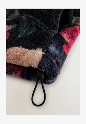 Fleece-tæppe med floral mønster i mørke farver, med en blød tekstur og en lyserød bagside. Inkluderer en sort snøredetalje.