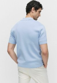 Ljusblå kortärmad polo i mjuk bomull med krage och en figurnära design. Har ribbade detaljer vid fåll och ärmar.