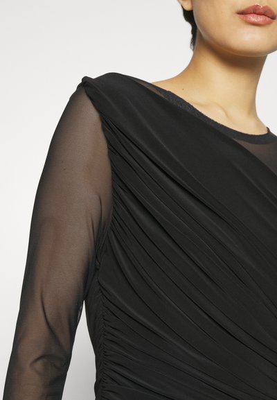 Czarna sukienka o gładkiej, drapowanej teksturze i przezroczystych długich rękawach; posiada fałdy na korpusie oraz okrągły dekolt.