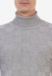 Grijze coltrui met een textuur van een ruitpatroon, met een geribde kraag en zachte gebreide stof.