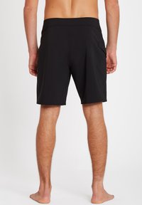 Shorts de bain noirs, fabriqués à partir de matériau léger, avec une taille plate et une poche latérale unique. Texture lisse, design à mi-cuisse.