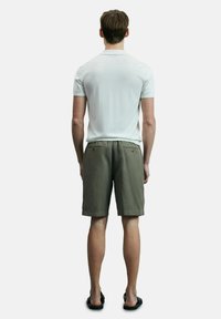 Lichtgrijs polo shirt met korte mouwen, gecombineerd met olijfgroene shorts met achterzakken. Sandalen maken de outfit compleet.
