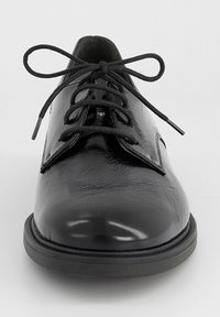 Chaussure Oxford noire en cuir brillant à lacets, bout rond et semelle épaisse en caoutchouc, vue de face sur fond blanc.