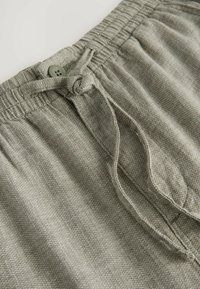 Grå shorts med elastisk talje har en bundet snor, knapaccent, tekstureret stof med et subtilt mønster og sidelommer.