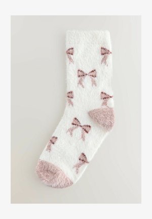 Szöszös fehér zokni, rózsaszín masnis mintával és egyszínű rózsaszín szöszös lábujjrésszel. Puha tapintású, bordás mandzsettával a kényelmes illeszkedés érdekében.