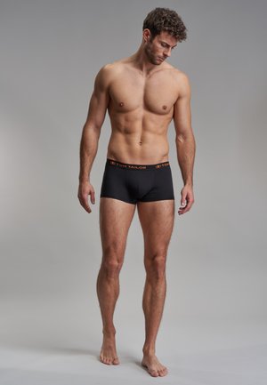 Schwarze Baumwollboxershorts mit einem elastischen Bund, der ein oranges "TOM TAILOR"-Logo trägt; glatte Textur und enganliegendes Design.