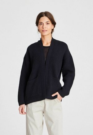 Cardigan lavorato a maglia blu navy con una texture a coste, apertura davanti e due tasche frontali. Presenta spalle scese e maniche larghe.