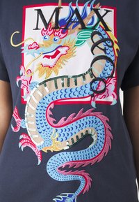 Granatowy t-shirt z kolorową grafiką smoka zdobioną cekinami i haftem, oprawioną w czerwony kwadrat oraz wyrazistym napisem "MAX".