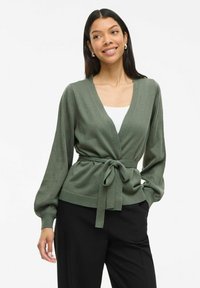 Cardigan verde de punto con escote en V, mangas largas tipo globo y cinturón en la cintura. Presenta un patrón texturizado y puños y dobladillo acanalados.