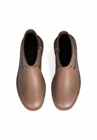 Scarpe in pelle marrone con una finitura liscia, dotate di chiusura con zip e punta leggermente arrotondata. Le suole sono piatte e rigide.