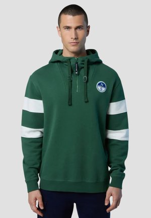 Felpa verde con righe bianche, colletto con zip, cordini regolabili e logo circolare sul petto. Tessuto morbido e vestibilità rilassata.