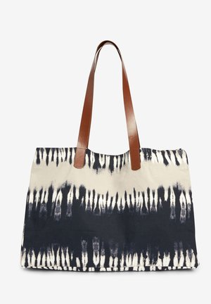 Sac en toile présentant un motif tie-dye bleu marine et crème avec deux anses en cuir marron. Conception rectangulaire robuste avec une surface texturée.