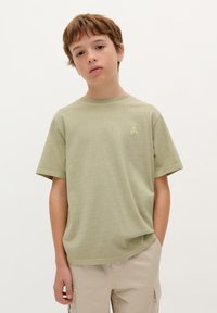 Lichtgroen katoenen T-shirt met een ronde hals, korte mouwen en een klein schedellogo in een iets lichtere tint op de borst.