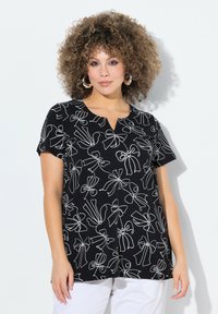 Top negro de manga corta con un patrón de lazo blanco y diseño de escote en V. Fabricado en un material suave, con un ajuste relajado y bajo curvado.